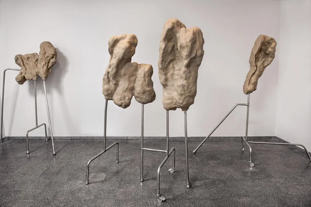 Organic sculptural forms resting on slender metal stands at Maya Gallery.