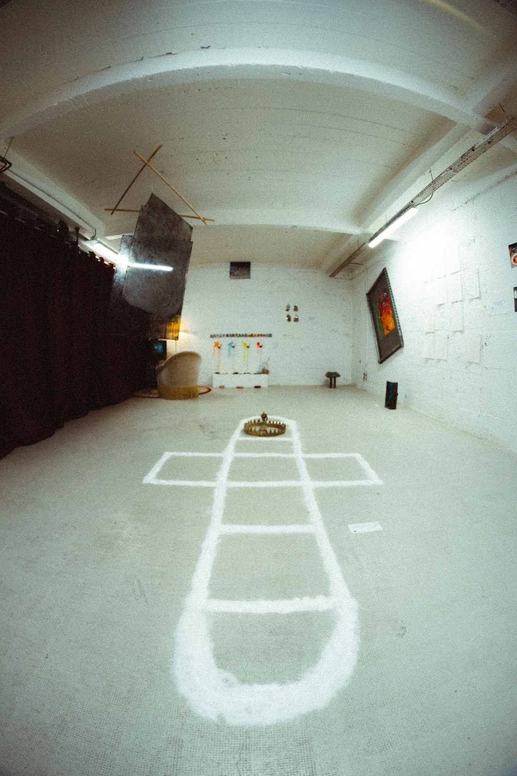 A long view through the exhibition with a white outlined form on the gallery floor.