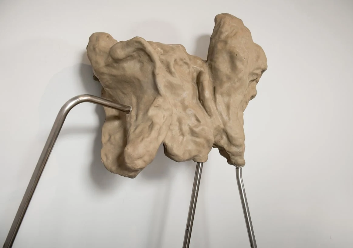 A broad sculptural form held by an asymmetric stand with a sweeping metal arm.