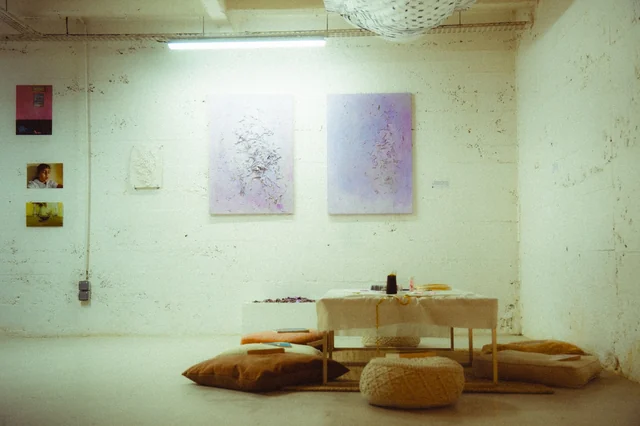 Artworks above a low table and cushions in the exhibition at La Corvée Galerie.