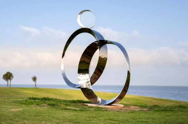 Reflective sculptural rings above the grass and sea at Midron Park, Jaffa.