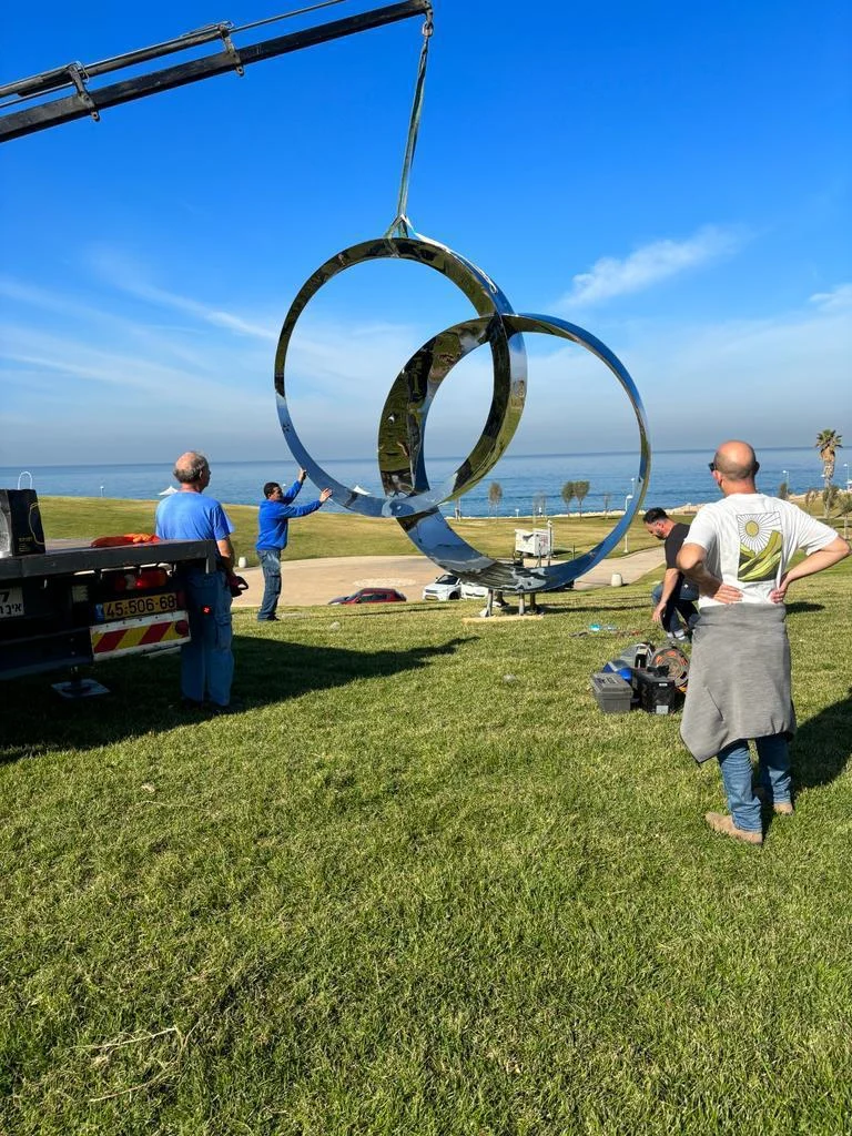 The sculpture being lifted into position at the park with the sea behind.