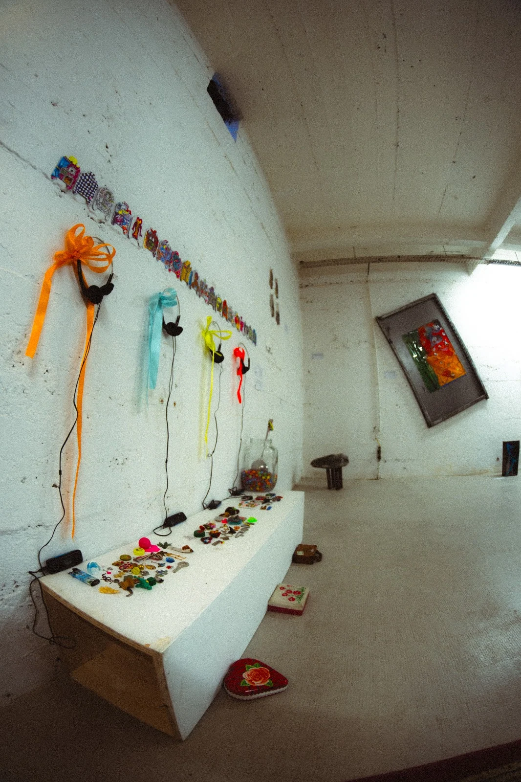 A portrait view along the gallery wall, showing small objects, ribbons and artworks.